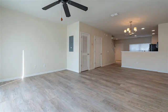 a view of an empty room with kitchen and chandelier