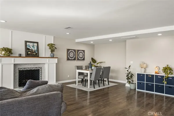 a living room with furniture a fireplace and a dining table with wooden floor