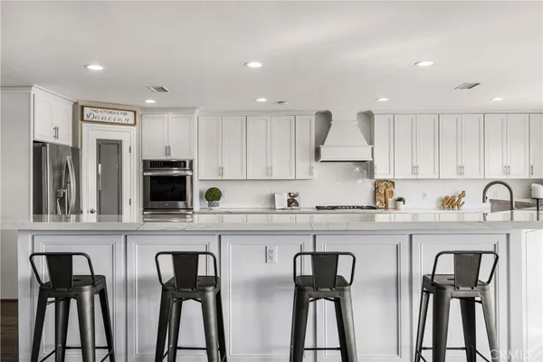 a kitchen with stainless steel appliances granite countertop a table chairs refrigerator and sink