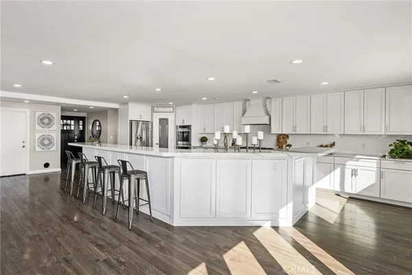 a kitchen with stainless steel appliances granite countertop a refrigerator a stove top oven and a dining table with wooden floor