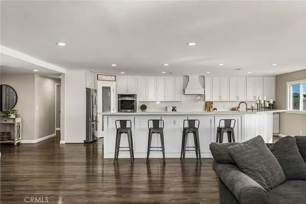 a living room with stainless steel appliances kitchen island furniture and wooden floor