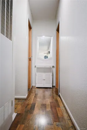 a view of a hallway with wooden floor and a bathroom