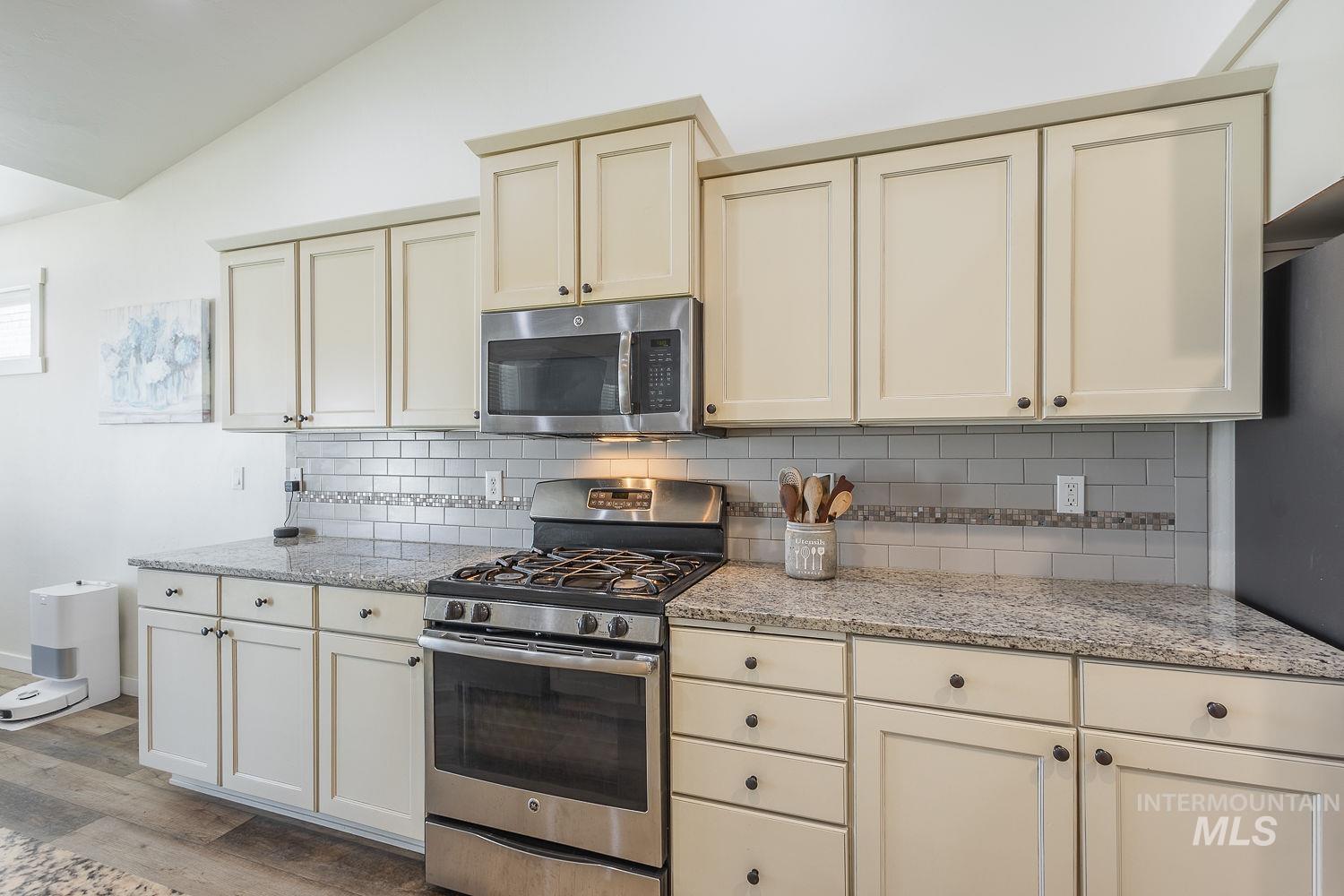 1332 West Raelin Drive Nampa, ID 83686 - Photo 12 of 48 Kitchen with stainless steel appliances, light stone countertops, backsplash, lofted ceiling, and light wood-style floors