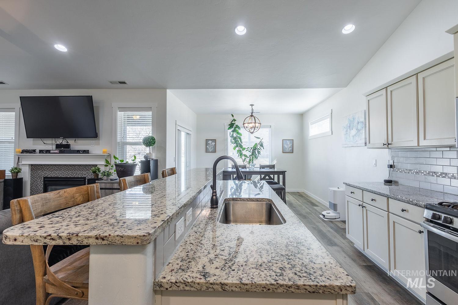 1332 West Raelin Drive Nampa, ID 83686 - Photo 14 of 48 Kitchen with light stone countertops, a breakfast bar, backsplash, wood finished floors, and recessed lighting