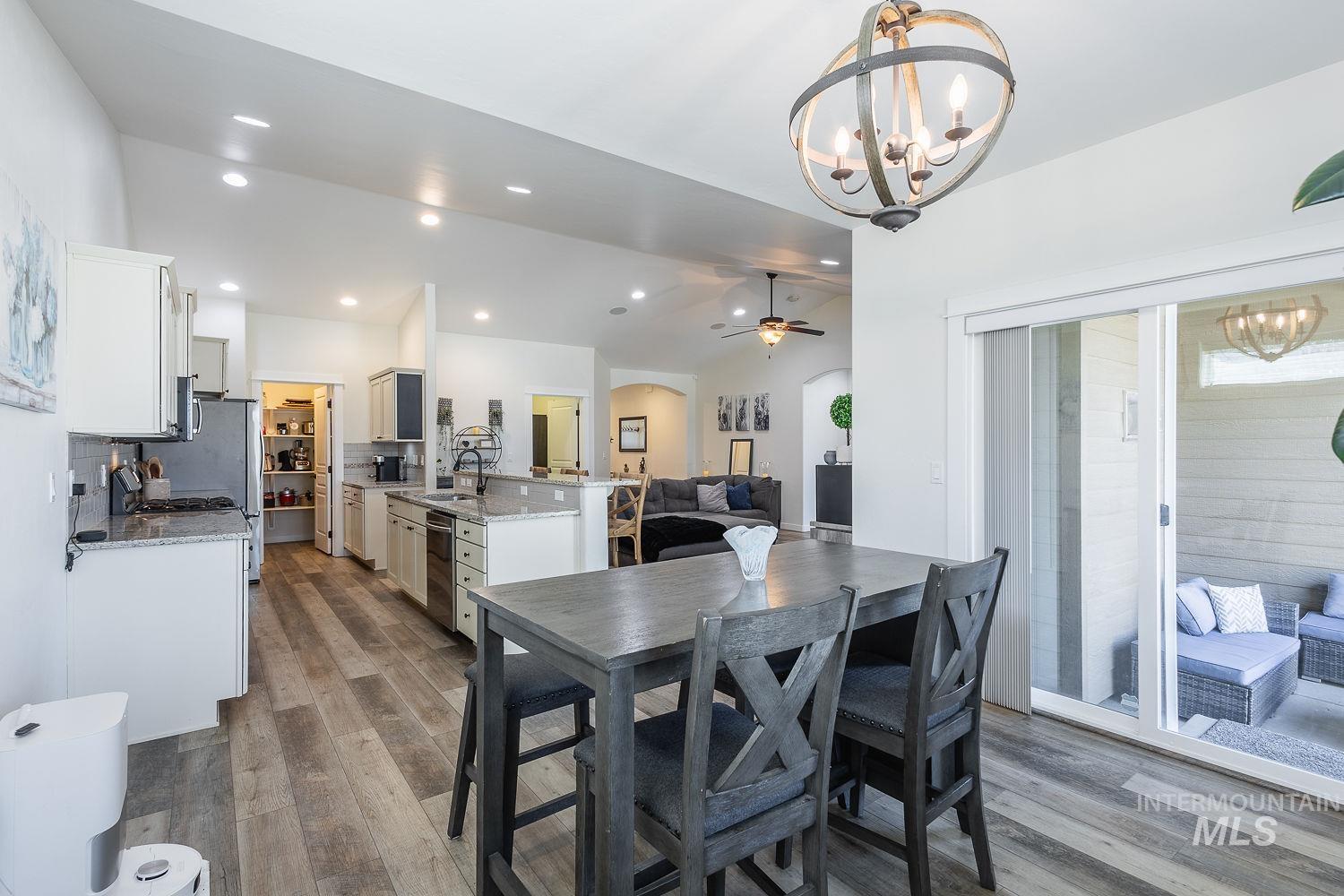1332 West Raelin Drive Nampa, ID 83686 - Photo 19 of 48 Dining space featuring lofted ceiling, a chandelier, arched walkways, dark wood-style flooring, and a ceiling fan