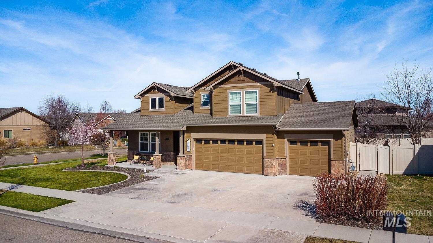 1332 West Raelin Drive Nampa, ID 83686 - Photo 2 of 48 Craftsman-style home with a porch, stone siding, driveway, roof with shingles, and an attached garage