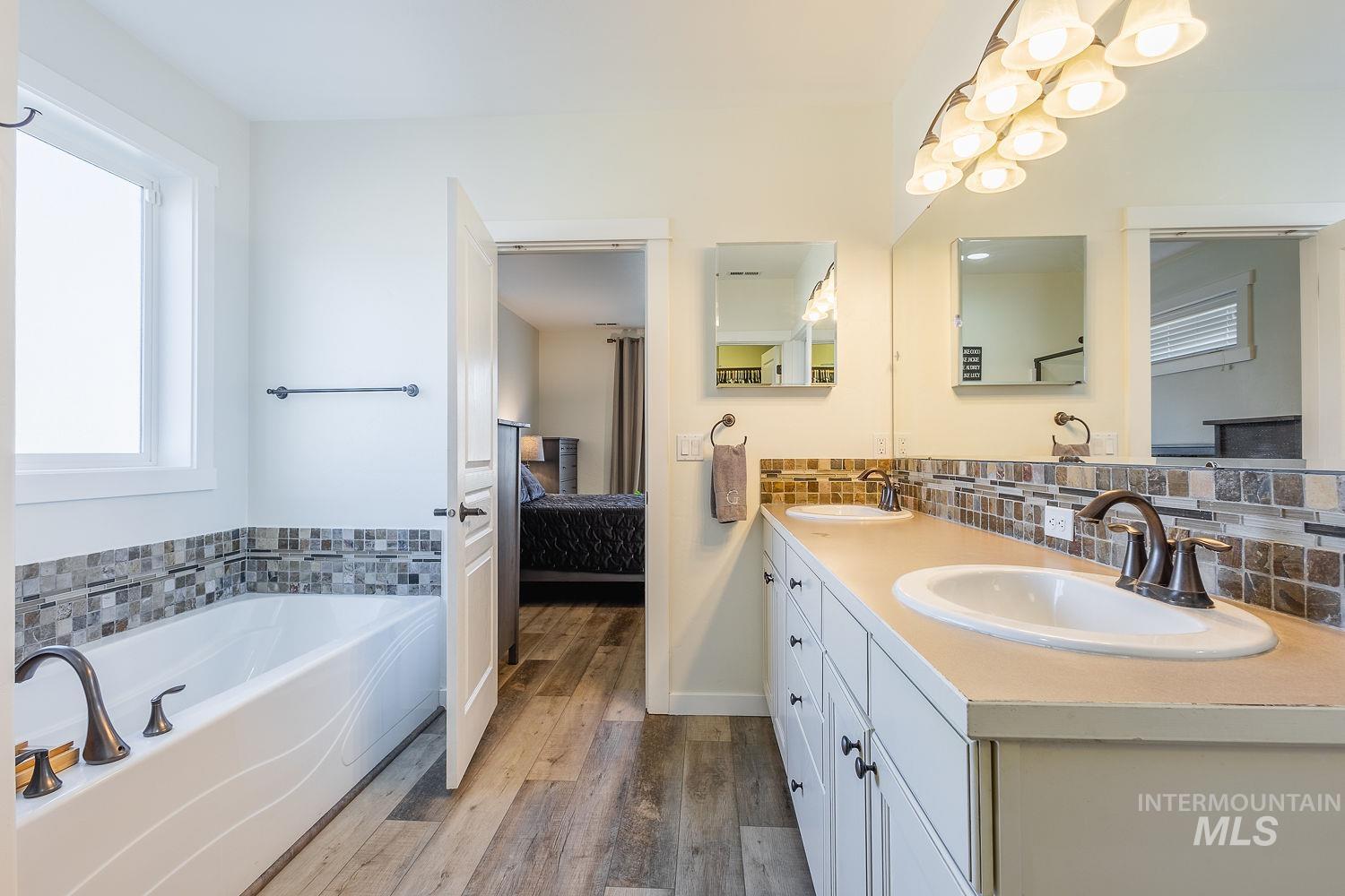 1332 West Raelin Drive Nampa, ID 83686 - Photo 27 of 48 Ensuite bathroom with double vanity, dark wood-style flooring, a garden tub, and decorative backsplash