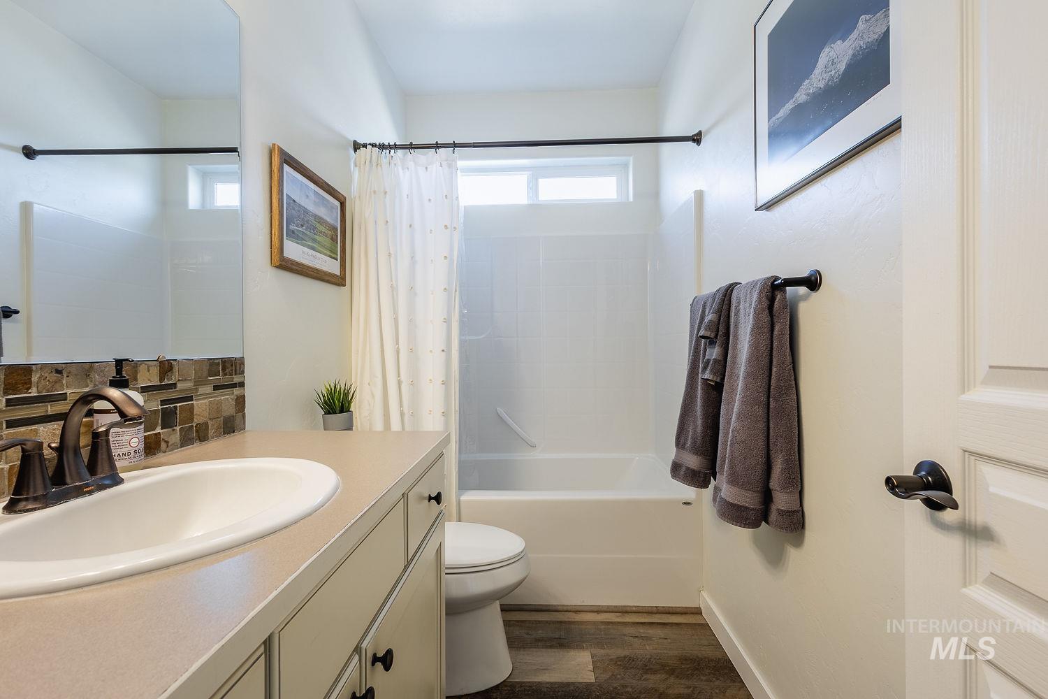 1332 West Raelin Drive Nampa, ID 83686 - Photo 34 of 48 Bathroom featuring vanity, shower / bath combo, dark wood-type flooring, and backsplash