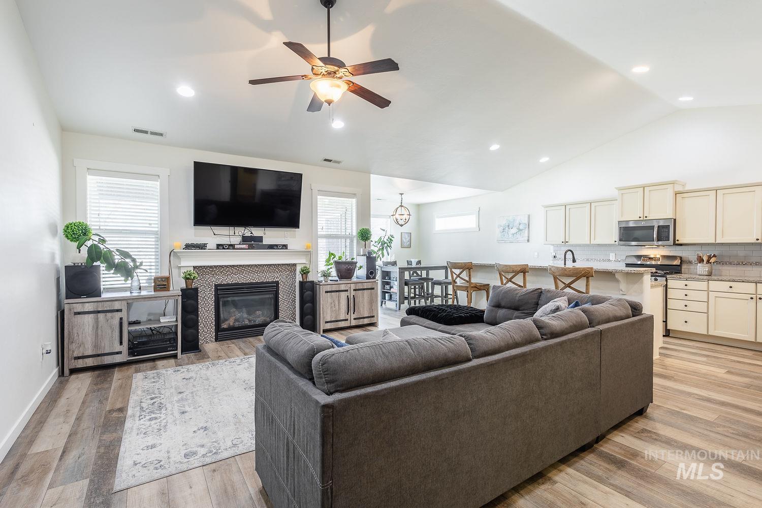 1332 West Raelin Drive Nampa, ID 83686 - Photo 7 of 48 Living room with ceiling fan, light wood-style floors, vaulted ceiling, recessed lighting, and a tiled fireplace