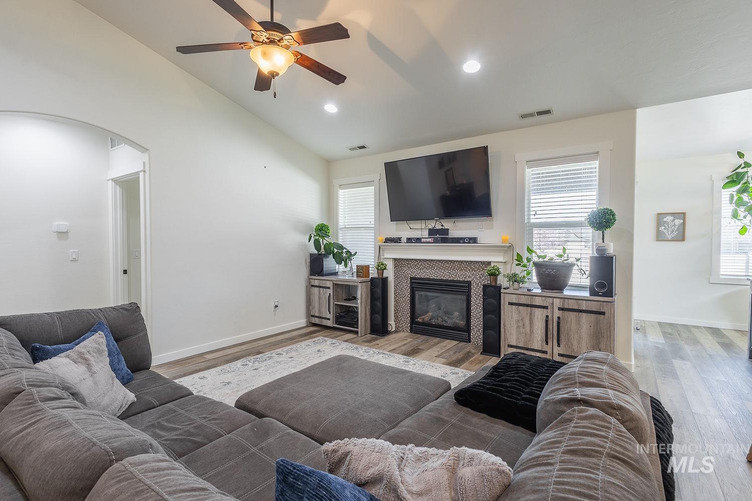 1332 West Raelin Drive Nampa, ID 83686 - Photo 8 of 48 Living room with arched walkways, light wood finished floors, vaulted ceiling, a ceiling fan, and a tiled fireplace