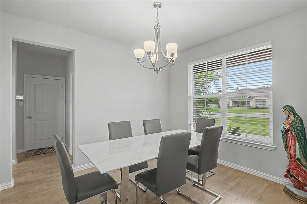 185 Chester Road Springtown, TX 76082 - Photo 10 of 40 Dining area featuring wood-finish flooring, a contemporary chandelier, and a large window with blinds