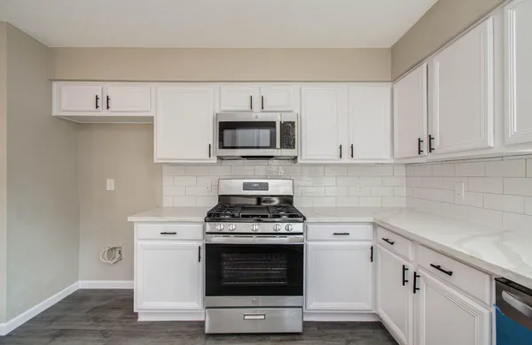 a kitchen with cabinets stainless steel appliances and wooden floor
