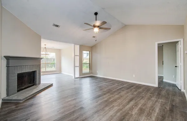 a view of an empty room with chandelier and fireplace