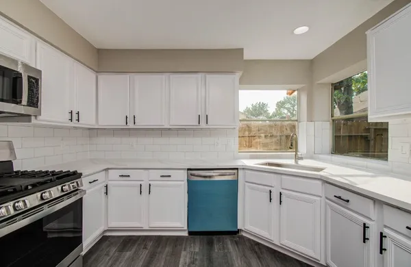 a kitchen with granite countertop white cabinets and stainless steel appliances