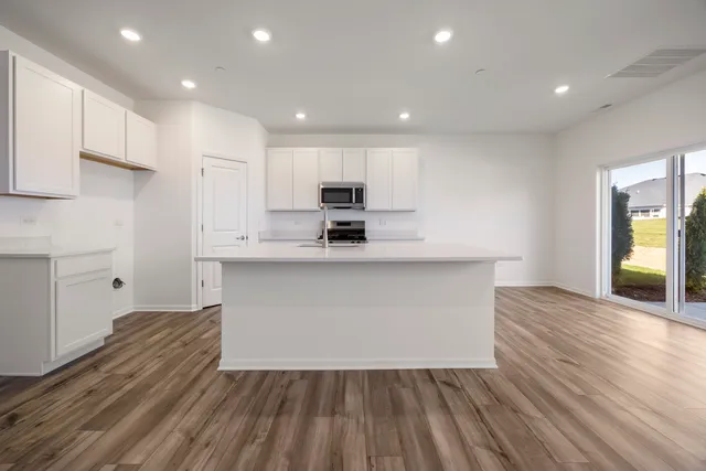 a kitchen with wooden floors and white cabinets