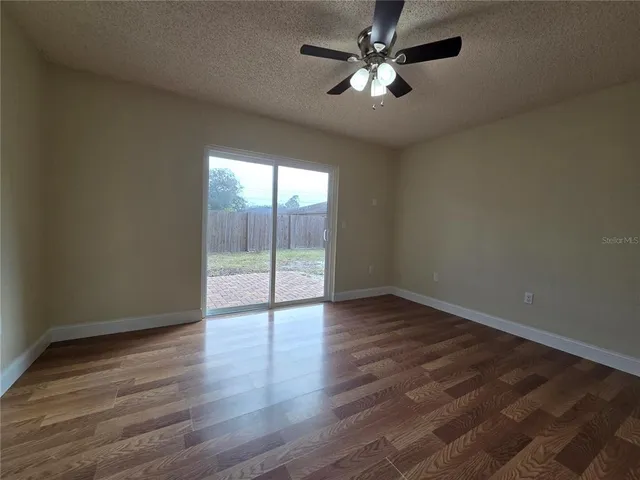 an empty room with wooden floor fan and windows