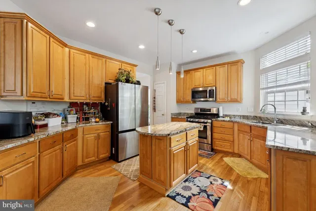 a kitchen with stainless steel appliances granite countertop a stove top oven a sink dishwasher a refrigerator and cabinets with wooden floor