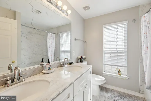 a bathroom with double vanity sinks a toilet and a mirror