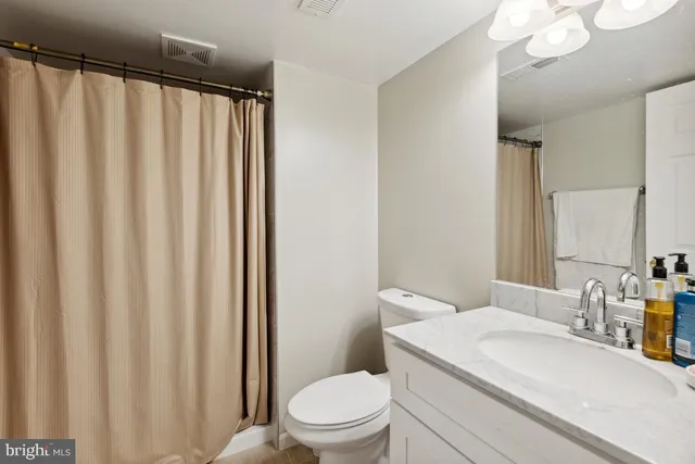 a bathroom with a granite countertop sink toilet and a mirror