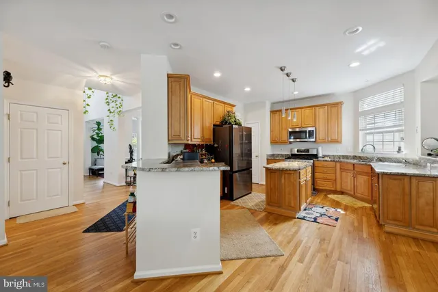 a kitchen with a refrigerator a stove top oven a sink dishwasher and wooden cabinets with wooden floor