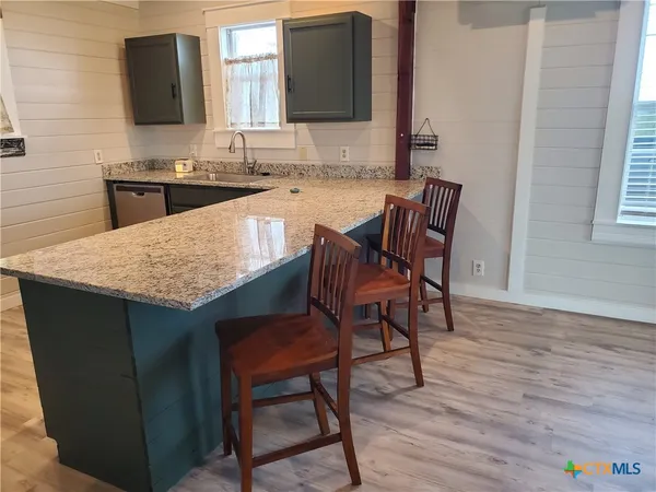 a kitchen with a wooden floor and chairs