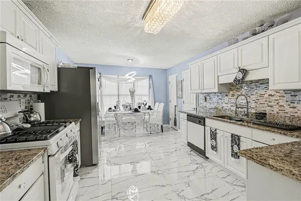 a kitchen with stainless steel appliances granite countertop a stove top oven a sink a refrigerator and cabinets