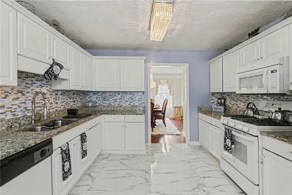 a kitchen with granite countertop white cabinets and white appliances