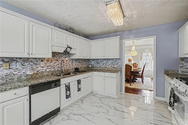 a kitchen with granite countertop a sink white cabinets and white appliances