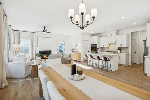 a view of a dining room and livingroom with furniture wooden floor a chandelier