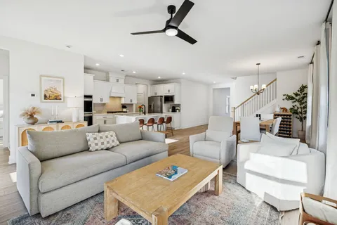 a living room with furniture kitchen view and a wooden floor