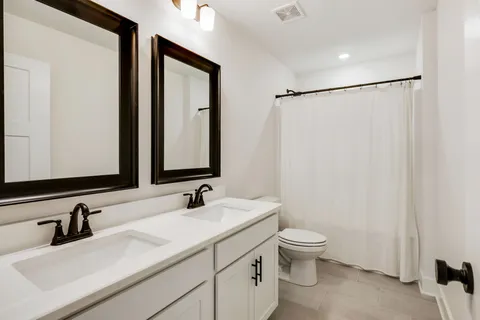 a bathroom with a double vanity sink toilet and mirror