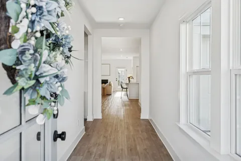 a view of a hallway with wooden floor and glass top table
