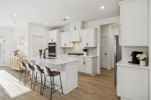 a kitchen with a sink a refrigerator and white cabinets