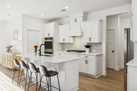 a kitchen with stainless steel appliances white cabinets a sink and a stove