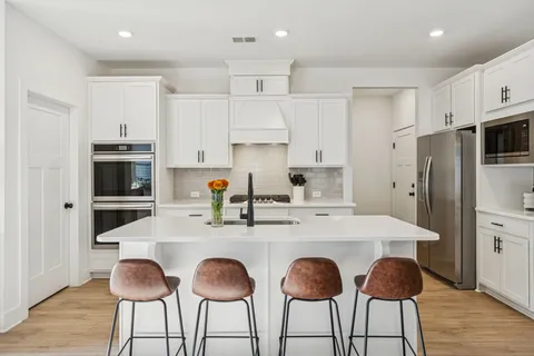 a kitchen with stainless steel appliances a dining table and chairs
