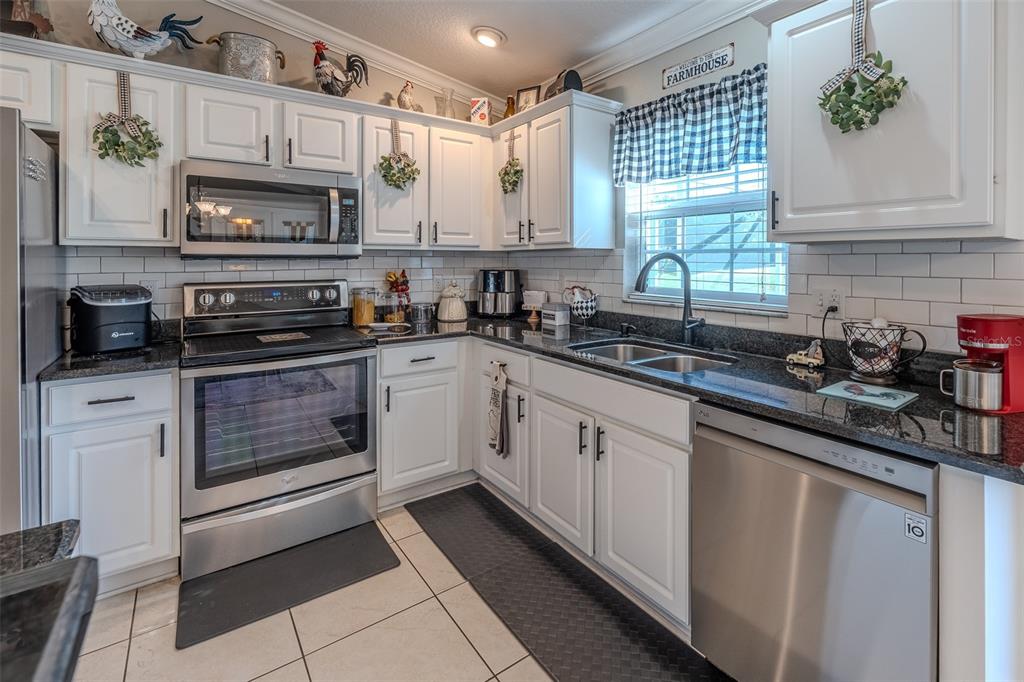 15143 Southwest 14th Avenue Road Ocala, FL 34473 - Photo 12 of 53 a kitchen with granite countertop white cabinets stainless steel appliances and a sink