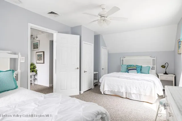 a sign that is sitting in front of a house with plants and trees