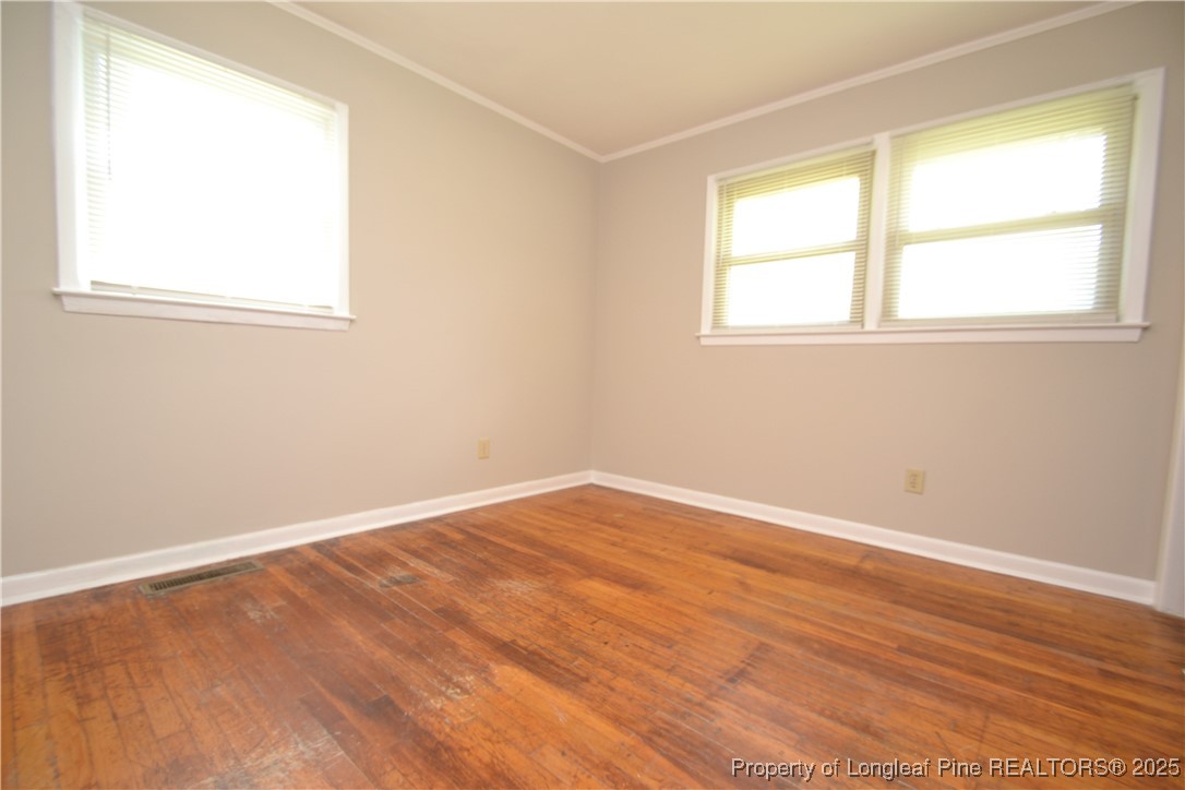 717 Friar Tuck Road Raleigh, NC 27610 - Photo 18 of 31 an empty room with wooden floor and windows
