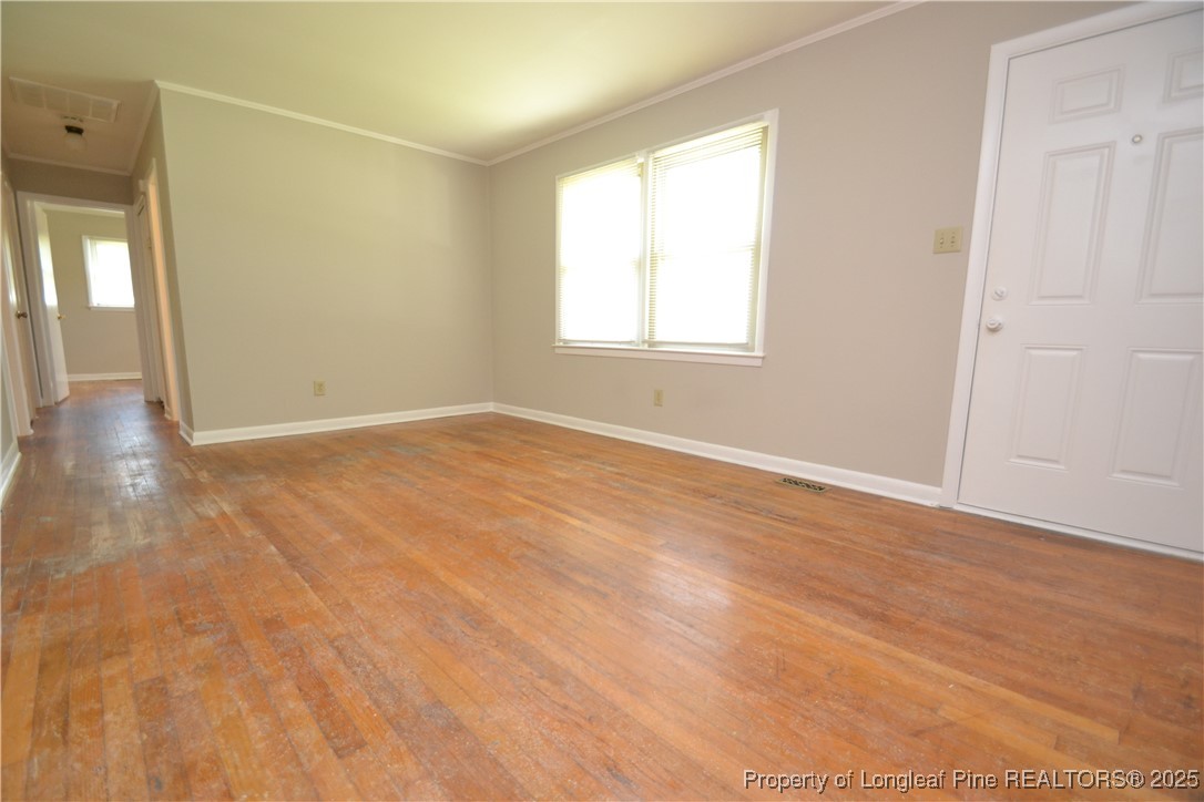 717 Friar Tuck Road Raleigh, NC 27610 - Photo 3 of 31 an empty room with wooden floor and windows