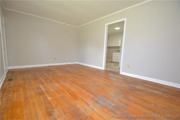 an empty room with wooden floor and a bathroom