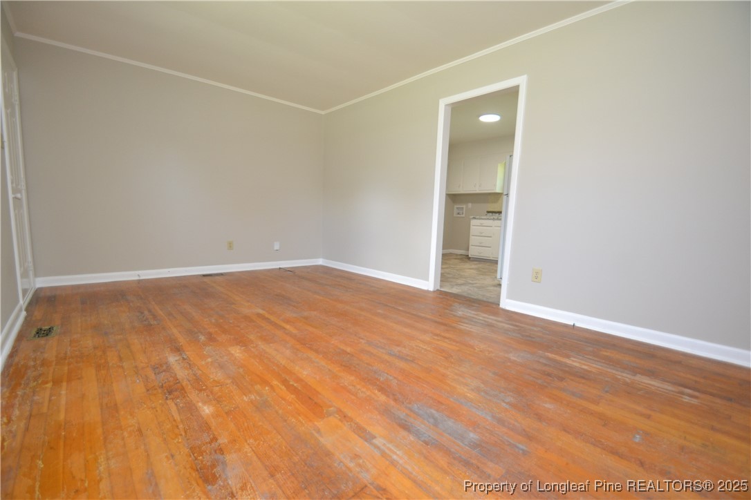 717 Friar Tuck Road Raleigh, NC 27610 - Photo 4 of 31 an empty room with wooden floor and a bathroom