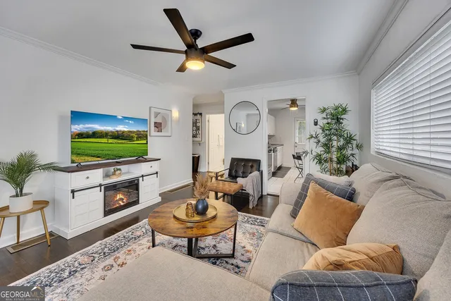 a living room with furniture a flat screen tv and a window