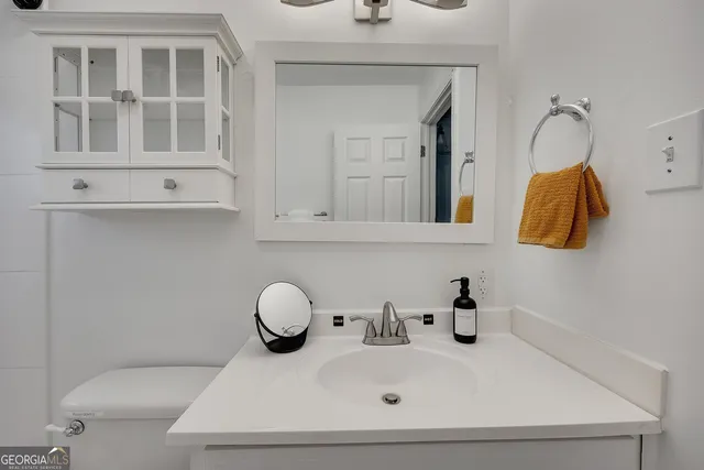 a bathroom with a sink and mirror with toilet