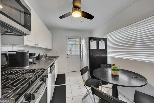 a kitchen with stainless steel appliances granite countertop a stove a sink dishwasher a dining table and chairs with wooden floor