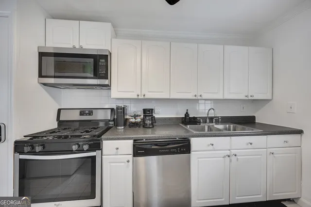 a kitchen with granite countertop white cabinets and stainless steel appliances