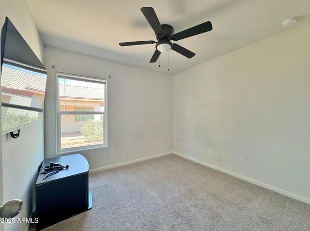 an empty room with ceiling fan and window