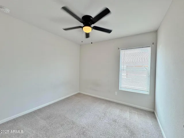 an empty room with ceiling fan and window