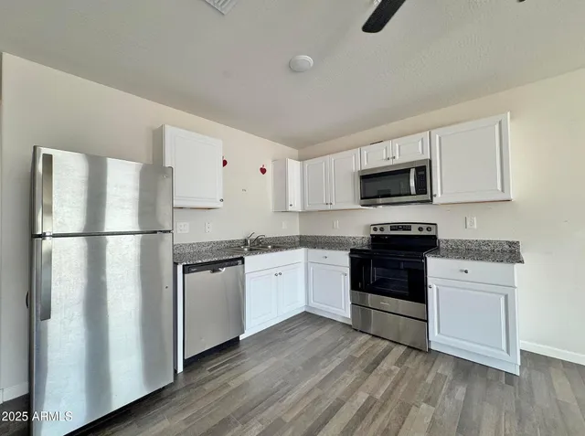 a kitchen with granite countertop a sink stainless steel appliances and wooden floor