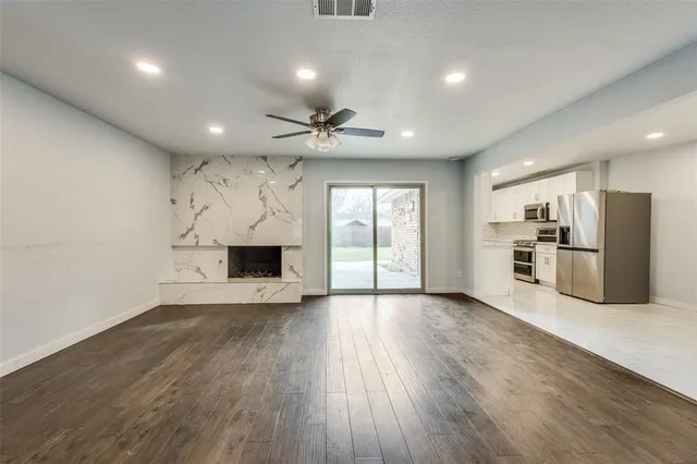 an empty room with wooden floor a fireplace and windows