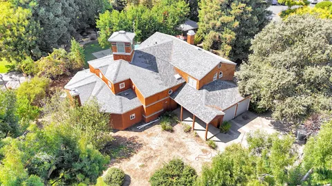 an aerial view of a house with yard and mountain view in back